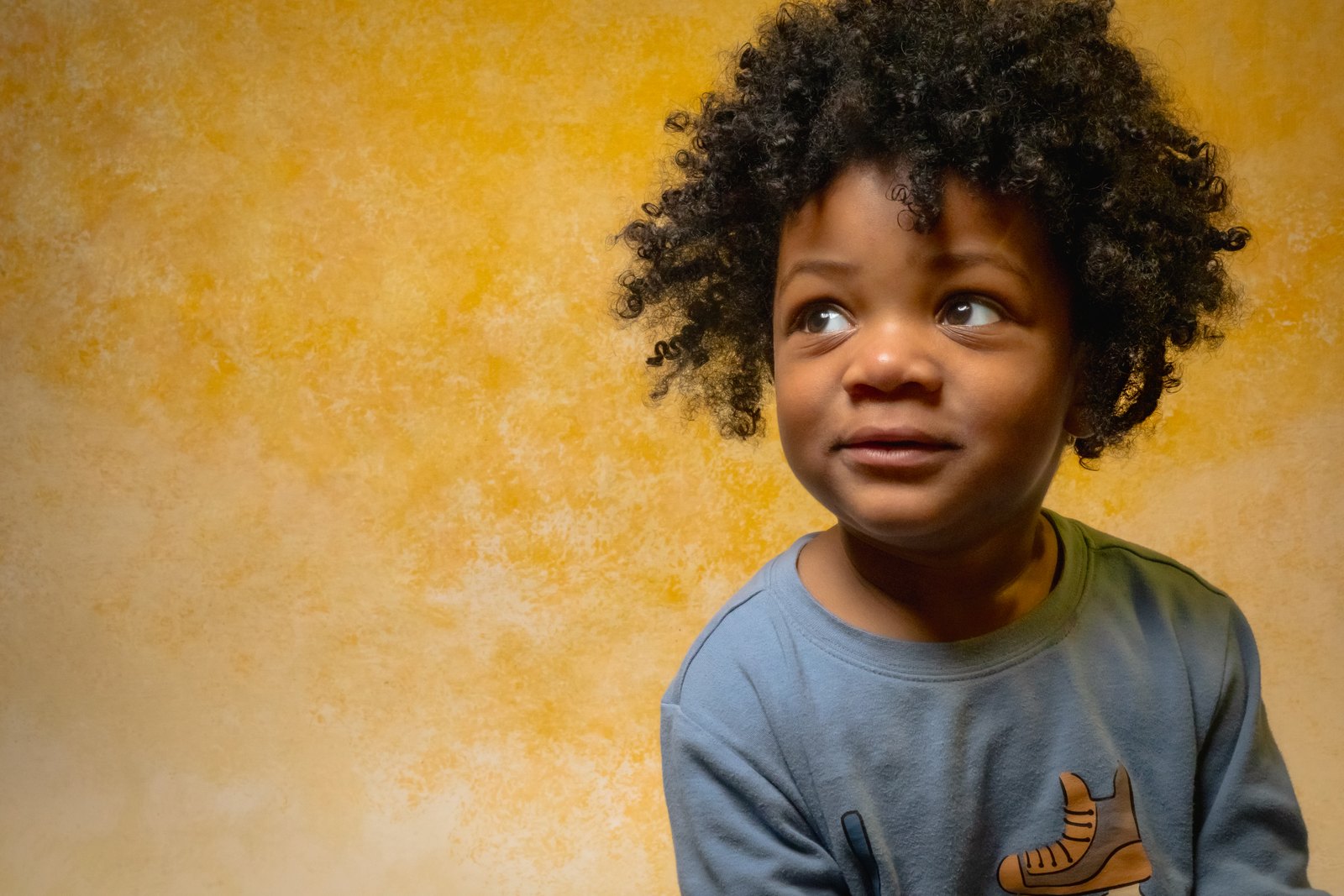 A boy grins tongue-out from a sea of marshmallow cereal, shot from above.