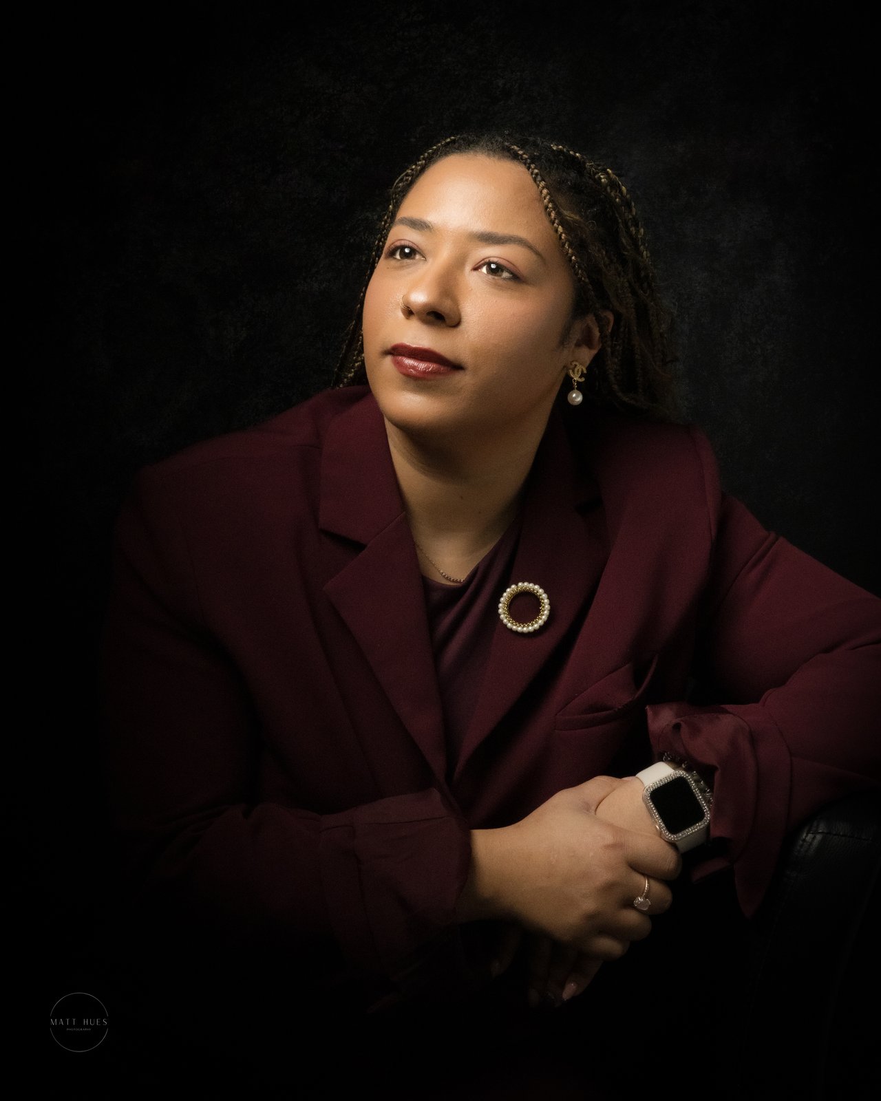A portrait in deep red gel light, hand raised near the face, a level gaze.
